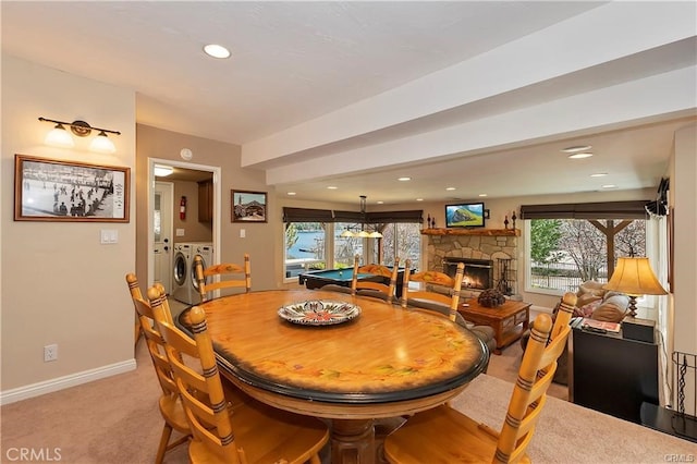 dining space featuring a fireplace, light carpet, and washing machine and clothes dryer