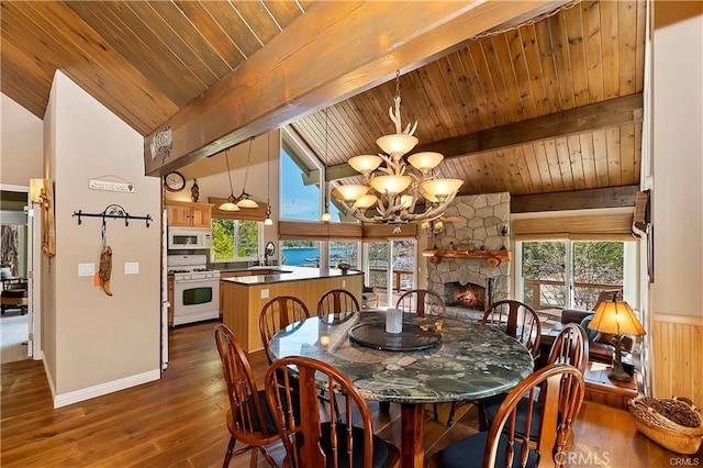 dining space featuring vaulted ceiling with beams, dark wood-type flooring, and a healthy amount of sunlight