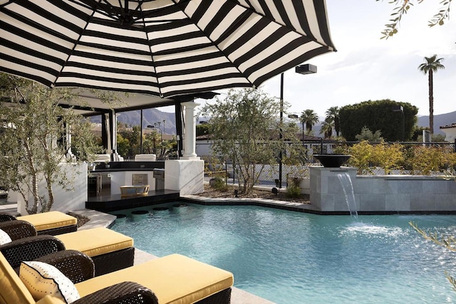 view of pool with pool water feature and exterior kitchen