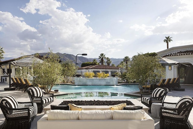 view of pool featuring pool water feature, a mountain view, and an outdoor hangout area