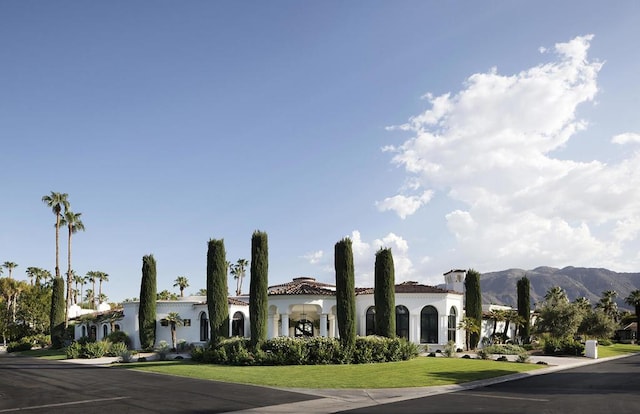 view of front of home with a mountain view and a front lawn