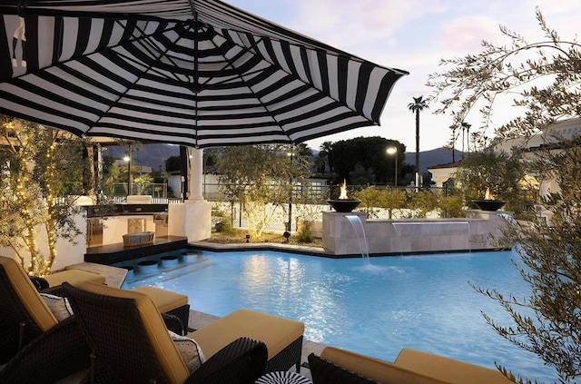 view of swimming pool featuring pool water feature, an outdoor kitchen, and a jacuzzi