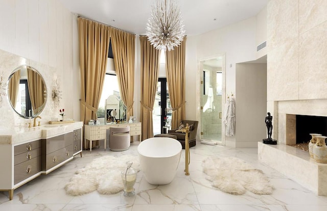 bathroom with a towering ceiling, vanity, independent shower and bath, and a notable chandelier