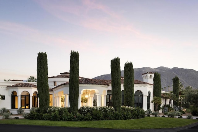 mediterranean / spanish house with a mountain view and a lawn