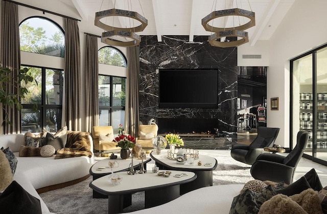 living room featuring beam ceiling, plenty of natural light, a high end fireplace, and high vaulted ceiling