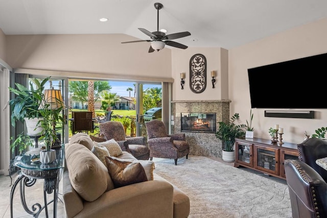 living room featuring ceiling fan, a tiled fireplace, and vaulted ceiling