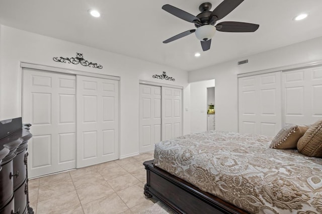 tiled bedroom with ceiling fan and two closets