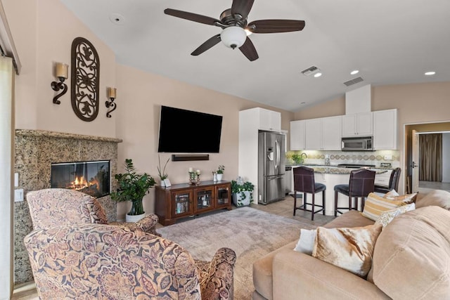 living room featuring ceiling fan, a high end fireplace, and lofted ceiling