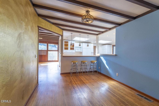 kitchen with beam ceiling, wood-type flooring, and decorative light fixtures