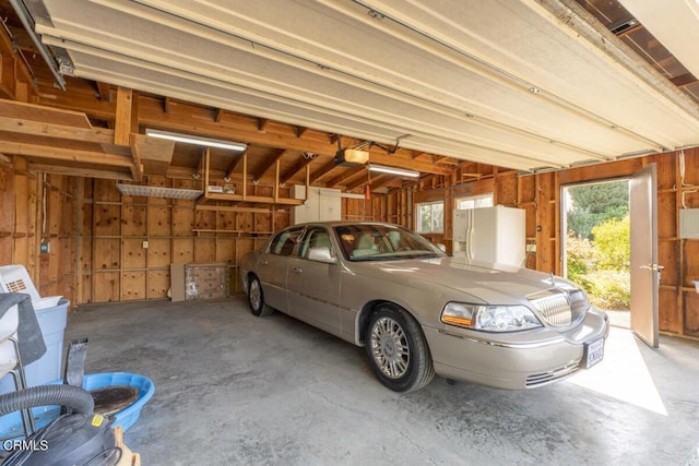 garage with white refrigerator with ice dispenser, a garage door opener, and wood walls