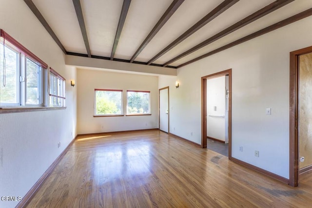 empty room featuring beam ceiling and hardwood / wood-style floors