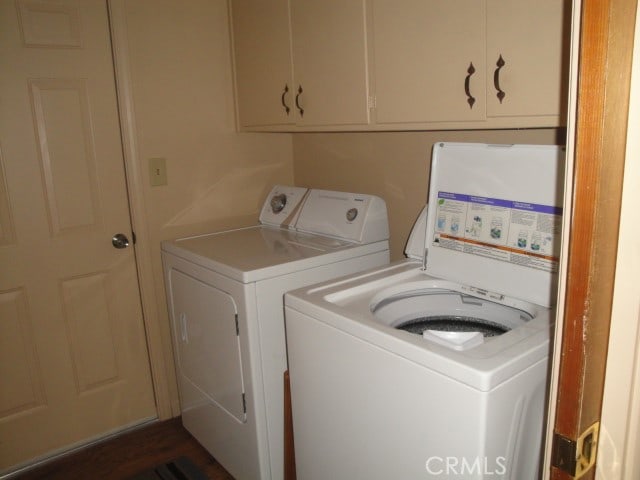 clothes washing area with cabinets and washing machine and clothes dryer