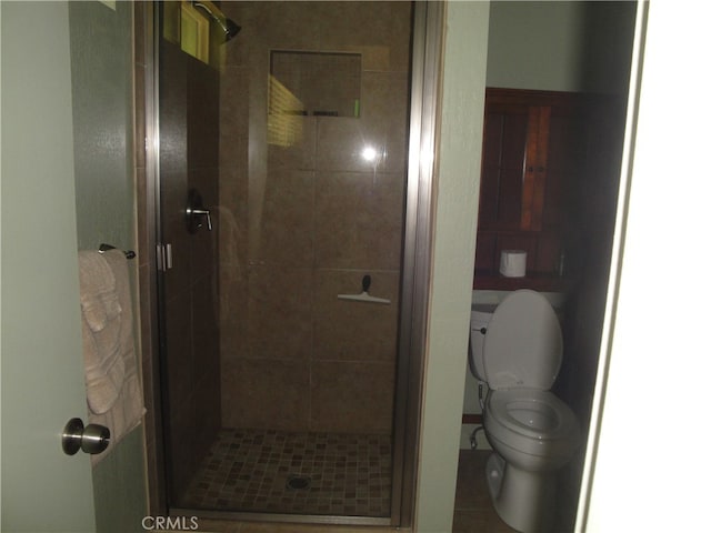 bathroom with tile patterned flooring, a shower with door, and toilet