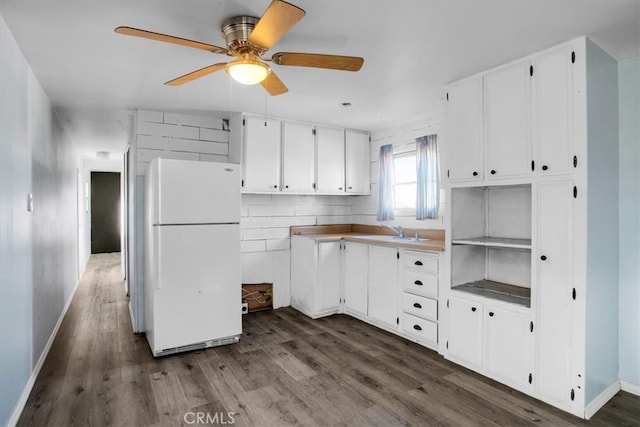 kitchen with ceiling fan, sink, white cabinetry, dark hardwood / wood-style floors, and white fridge