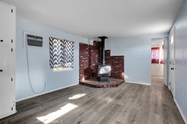 unfurnished living room with hardwood / wood-style floors, a wall mounted air conditioner, and a wood stove