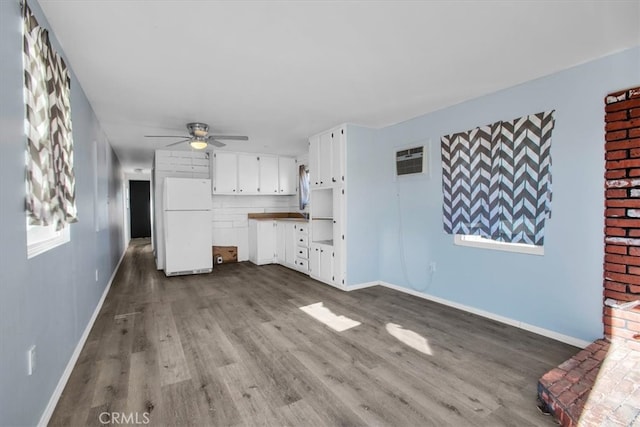 unfurnished living room featuring an AC wall unit, hardwood / wood-style floors, and ceiling fan