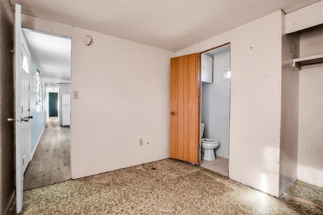 unfurnished bedroom with a closet, ensuite bathroom, and hardwood / wood-style floors