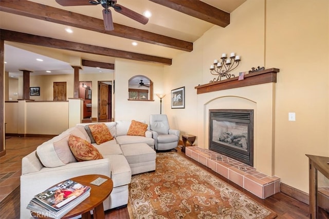 living room featuring beam ceiling, ceiling fan, a tile fireplace, and hardwood / wood-style floors