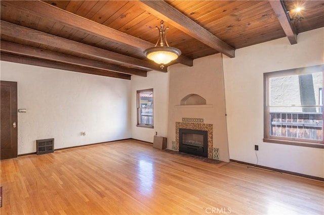 unfurnished living room with wood ceiling, a tiled fireplace, and light wood-type flooring