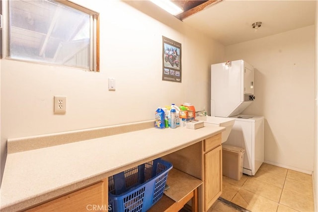 clothes washing area featuring stacked washer and dryer, light tile patterned floors, and cabinets