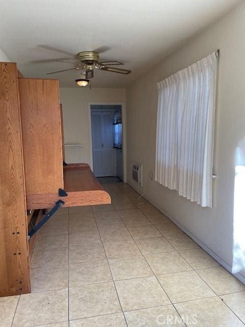 tiled spare room with ceiling fan and a wall unit AC