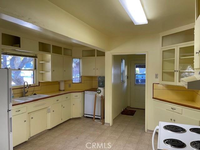 kitchen featuring white refrigerator, sink, tasteful backsplash, and range with electric stovetop