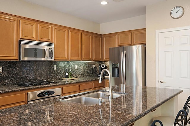 kitchen with backsplash, stainless steel appliances, dark stone counters, and sink