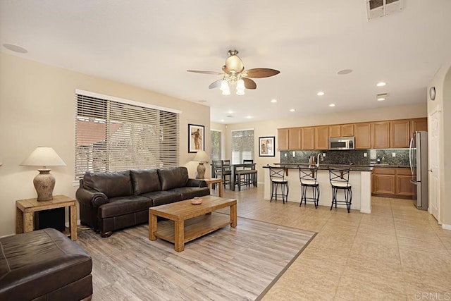 living area with ceiling fan, visible vents, and recessed lighting