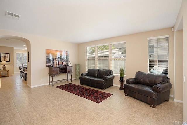 living area with visible vents, arched walkways, and baseboards