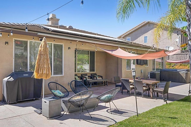 back of house featuring a patio area, a hot tub, a chimney, and stucco siding