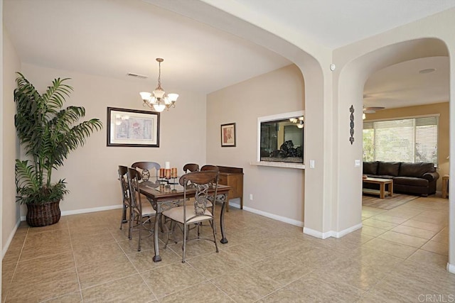 tiled dining room with arched walkways, an inviting chandelier, visible vents, and baseboards