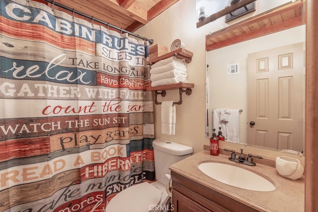 bathroom with curtained shower, vanity, toilet, and beamed ceiling