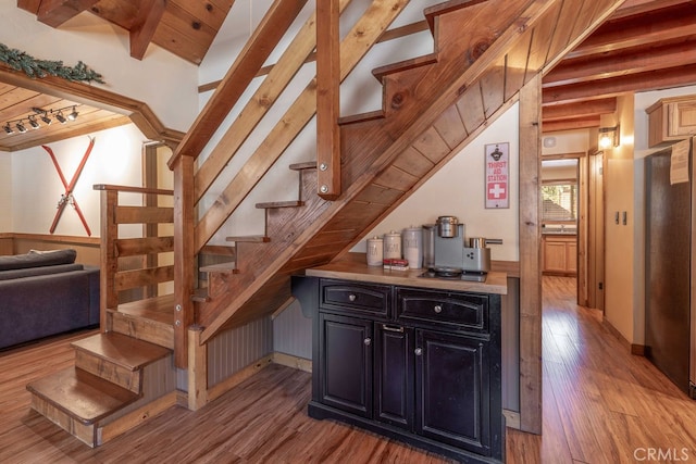 staircase with lofted ceiling with beams, wood ceiling, hardwood / wood-style flooring, and rail lighting