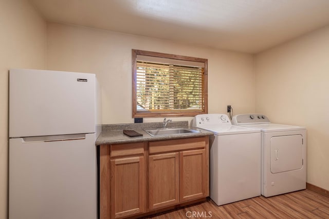 washroom with washer and clothes dryer, light hardwood / wood-style floors, and sink