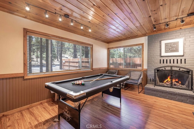 recreation room featuring wood ceiling, a brick fireplace, wood walls, and hardwood / wood-style flooring