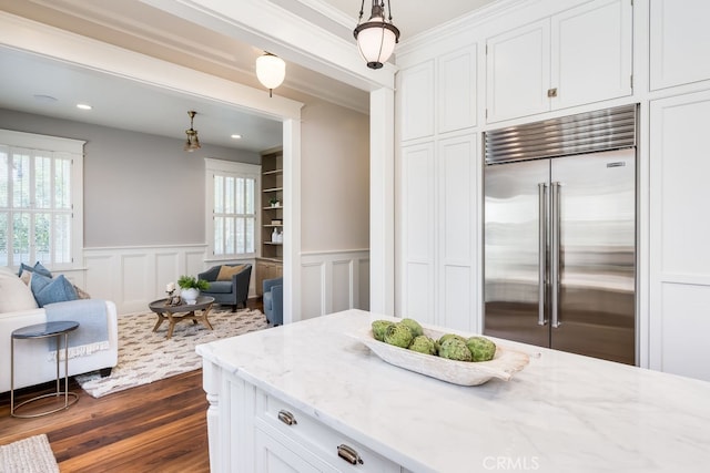 kitchen with hanging light fixtures, white cabinetry, dark wood-type flooring, light stone counters, and built in fridge