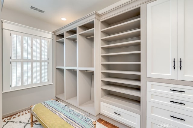 walk in closet with light hardwood / wood-style flooring