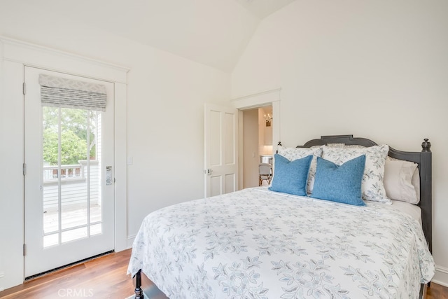 bedroom featuring access to outside, vaulted ceiling, and hardwood / wood-style floors