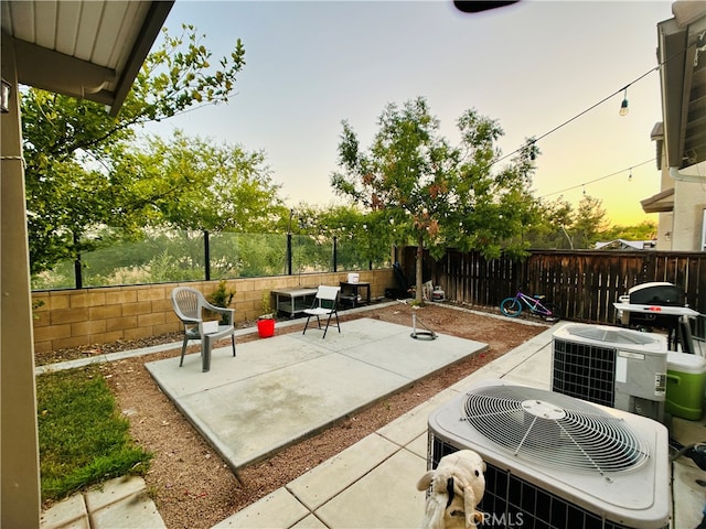 patio terrace at dusk featuring central air condition unit and a grill