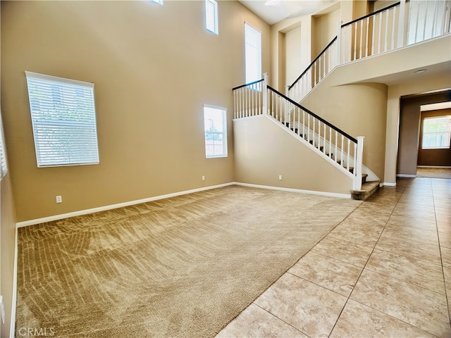 unfurnished living room with a towering ceiling, carpet, and a wealth of natural light