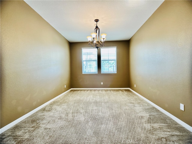 carpeted spare room featuring an inviting chandelier