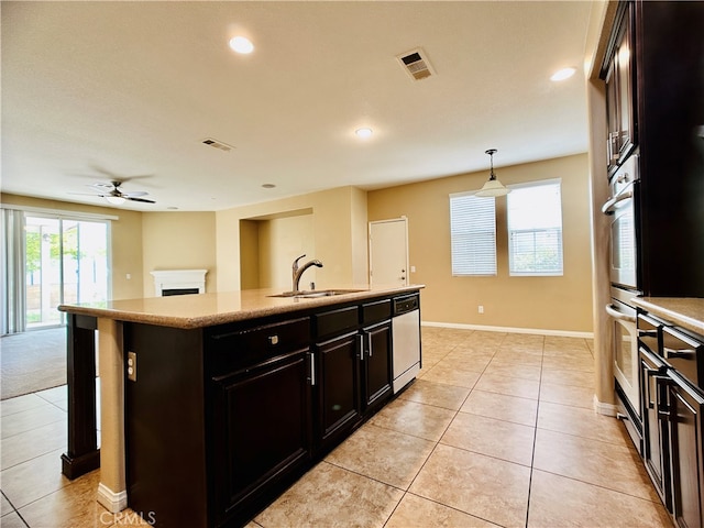 kitchen featuring an island with sink, hanging light fixtures, white dishwasher, sink, and light tile patterned flooring