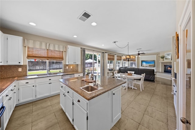 kitchen featuring tasteful backsplash, white cabinets, a kitchen island with sink, and sink