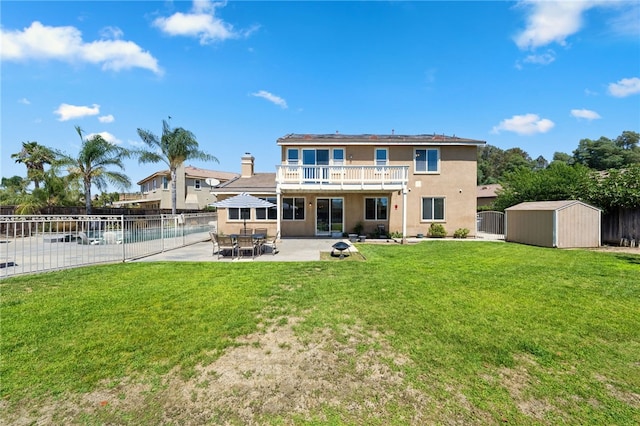 rear view of property with a storage shed, a lawn, a patio area, and a balcony