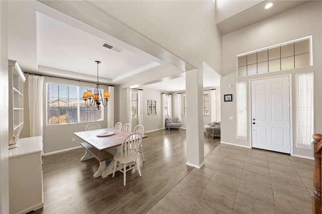 dining area featuring a raised ceiling, a notable chandelier, and hardwood / wood-style flooring