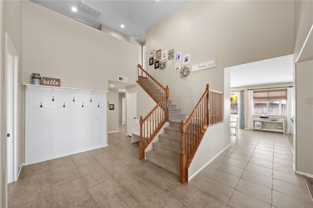 stairs with a towering ceiling and tile patterned flooring