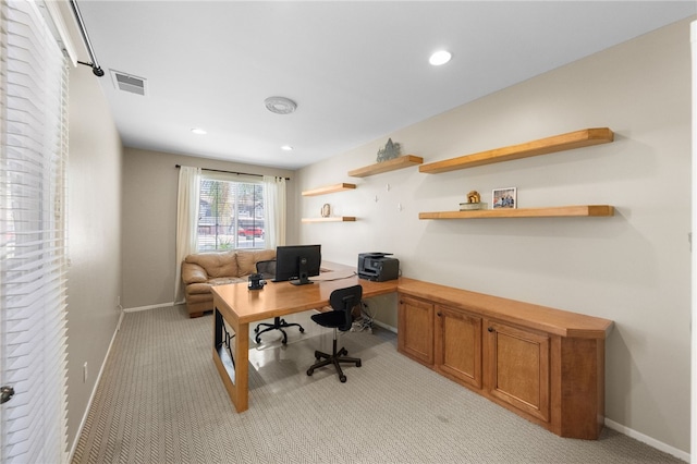 home office with light colored carpet and built in desk