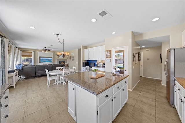 kitchen with a wealth of natural light, stainless steel refrigerator, a kitchen island, and white cabinetry