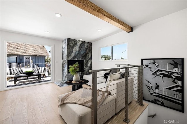 interior space featuring beamed ceiling, wood-type flooring, a premium fireplace, and access to outside