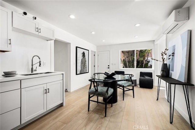 dining area with sink, a wall mounted air conditioner, and light hardwood / wood-style floors